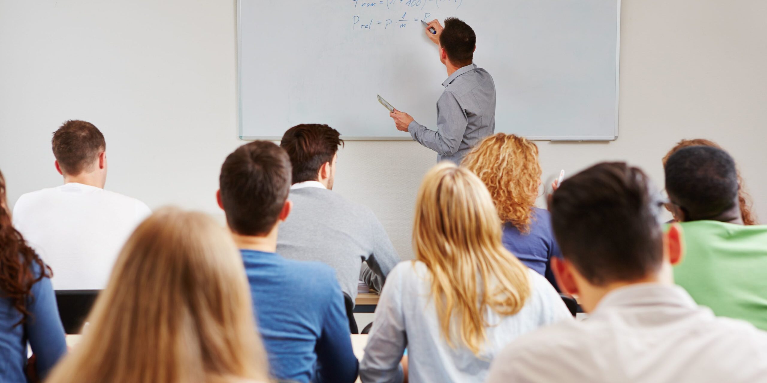 Professeur écrivant au tableau devant une classe