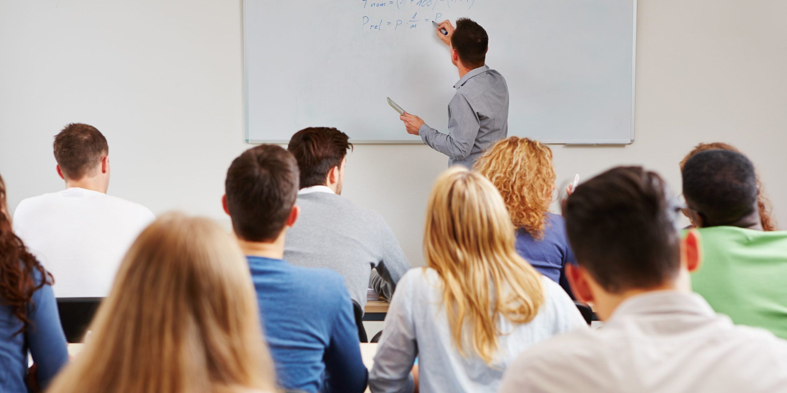 Image d'un professeur écrivant au tableau devant une classe. Représente le projet "Ecole du management"
